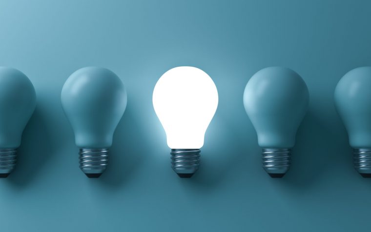 One glowing light bulb standing out from the unlit incandescent bulbs on green background with reflection and shadow , individuality and different business creative idea concepts . 3D rendering.