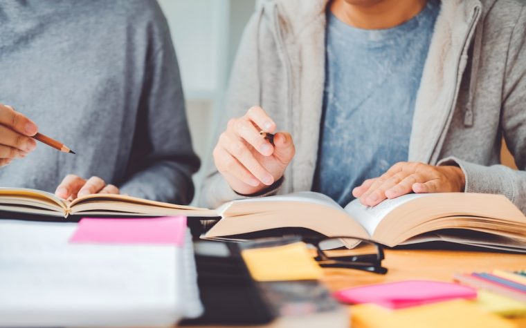 High school or college students studying and reading together in library